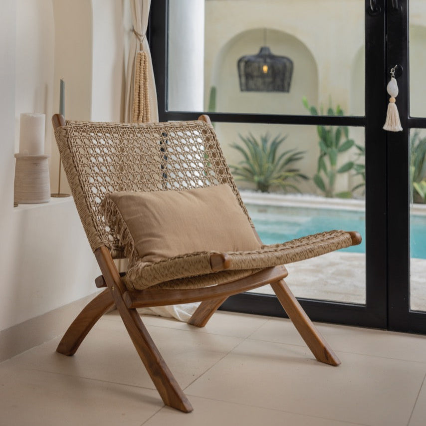 Boho Rattansessel Veala vor einer Glastür mit Pool im Hintergrund