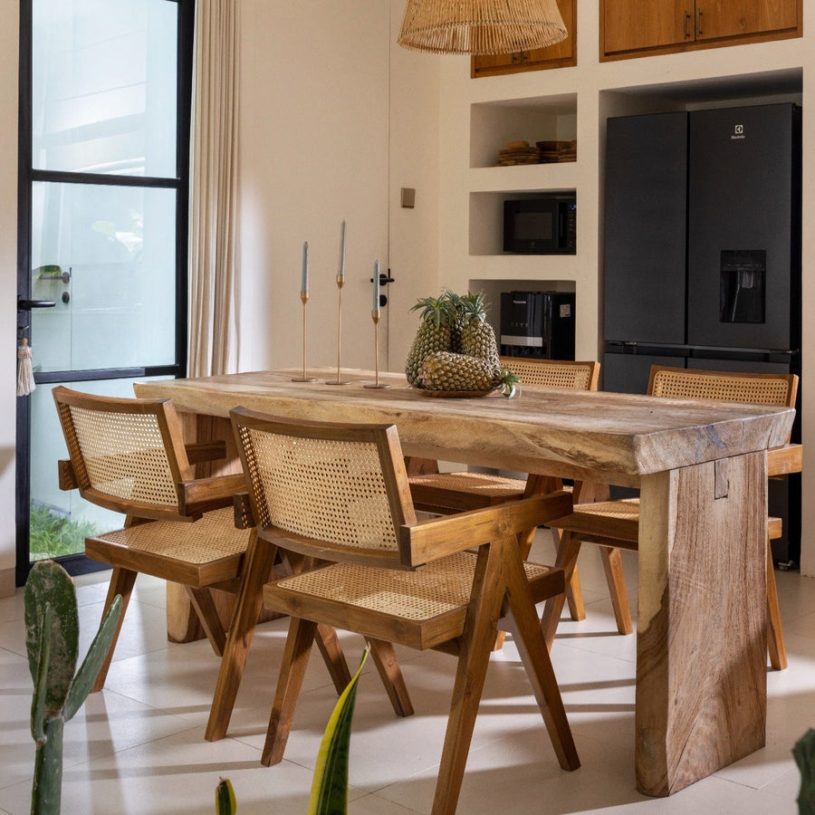 Essbereich mit Holztisch und Esszimmerstühlen aus Rattan