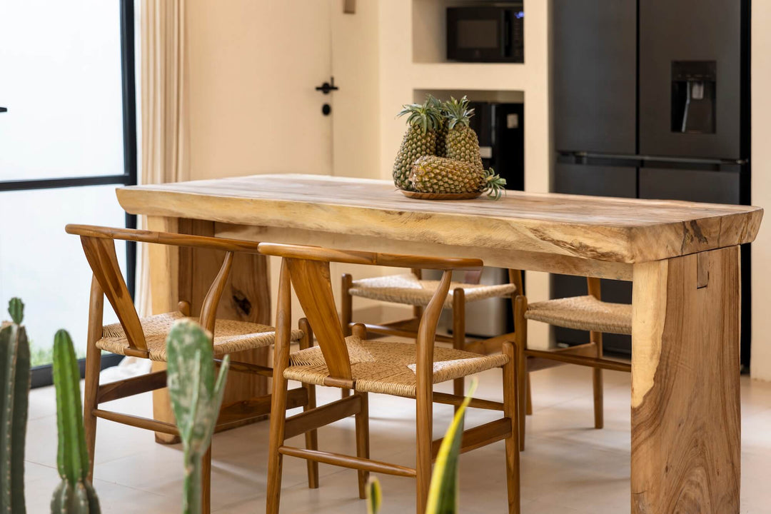 Esszimmerstühle Alara aus Teakholz stehen an einem massiven Holz-Esstisch