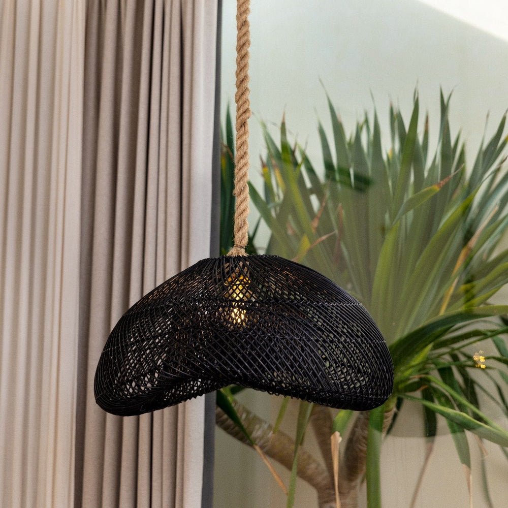 Schwarze Rattan Lampe Bayu Black hängt in einem Wohn- und Essbereich an der Decke