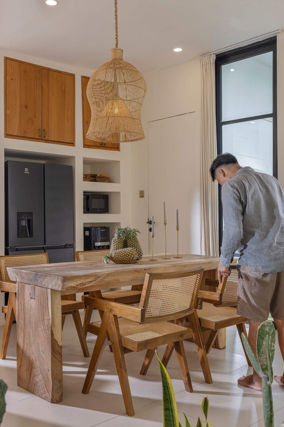 Mann schiebt Boho Esszimmerstuhl Vevani an den Tisch